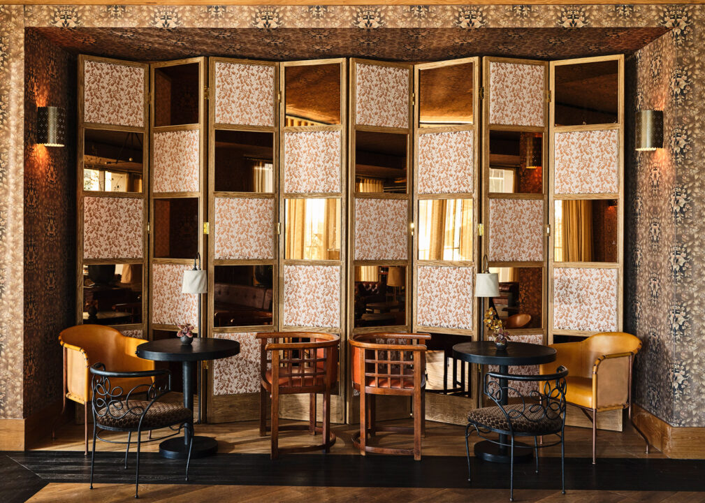 Cozy lounge nook with patterned screens, small tables, and stylish seating in a warm, vintage-inspired setting