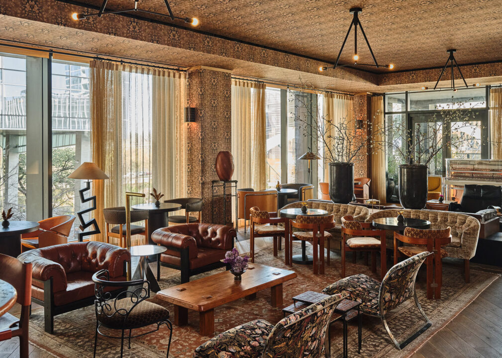 Elegant lounge with leather seating, patterned decor, large windows, and a warm, inviting ambiance
