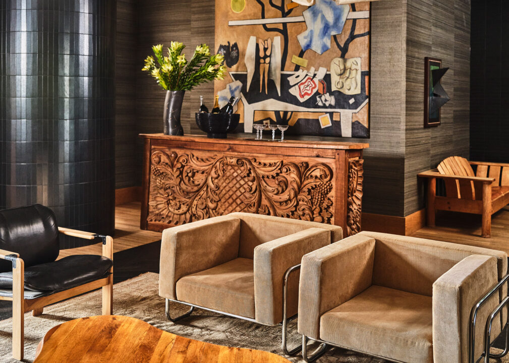 Cozy lounge with carved wood console, modern armchairs, and colorful artwork in quill room