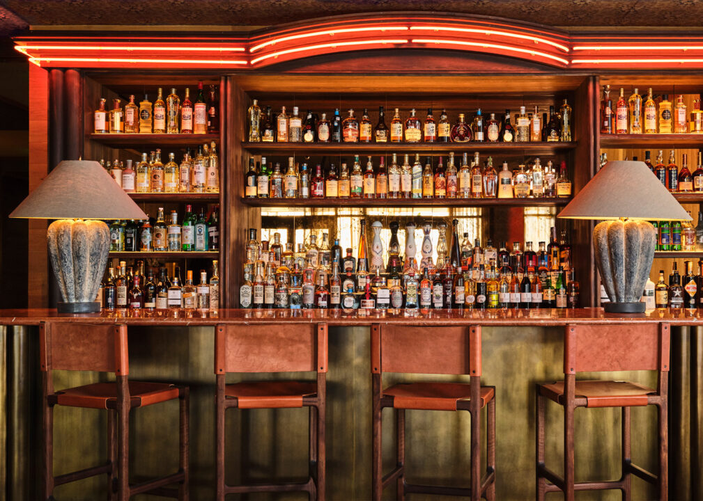 Stylish bar with leather stools, glowing red accents, and a curated wall of spirits