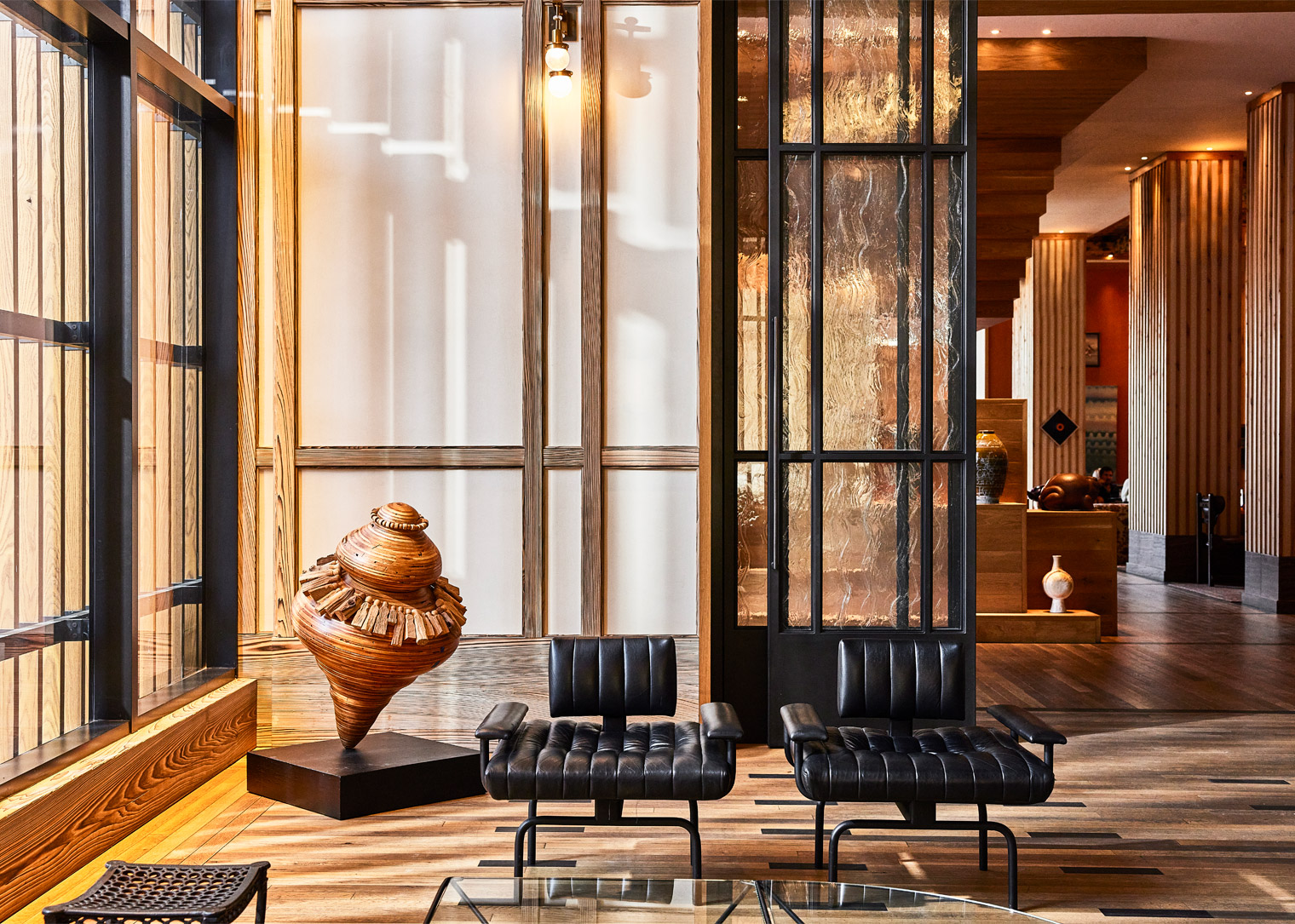 Modern lobby seating with sculptural wood art, black chairs, and glass partition