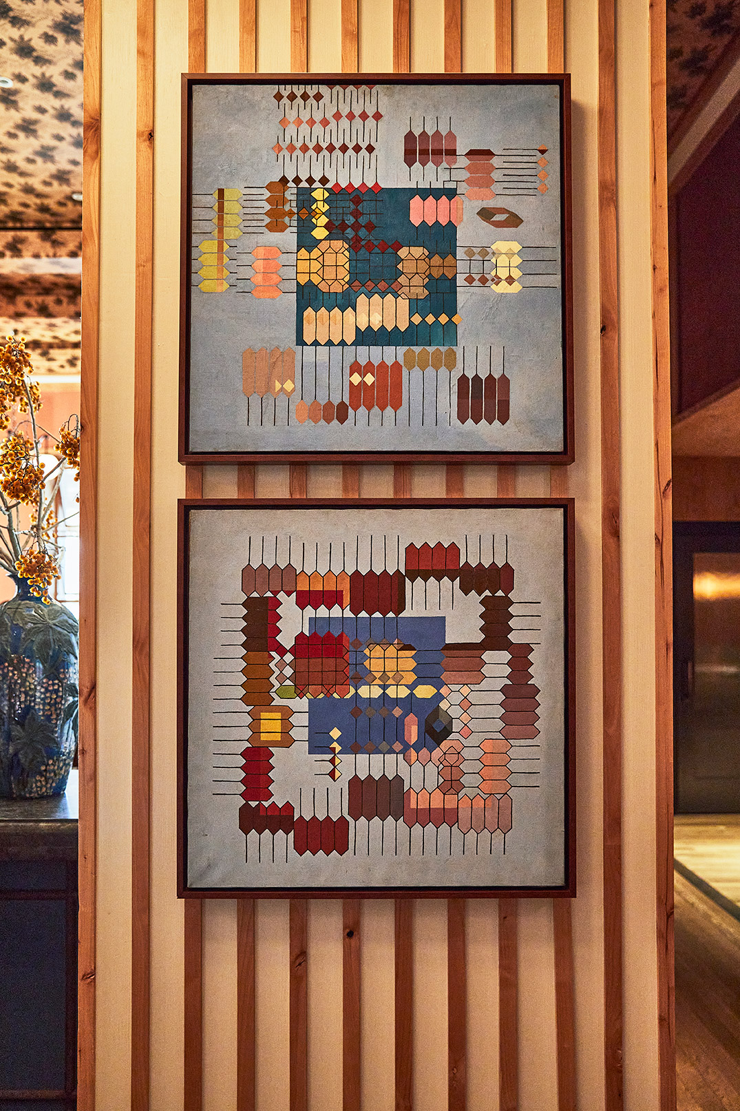 Framed geometric artwork on wood-paneled wall with warm tones