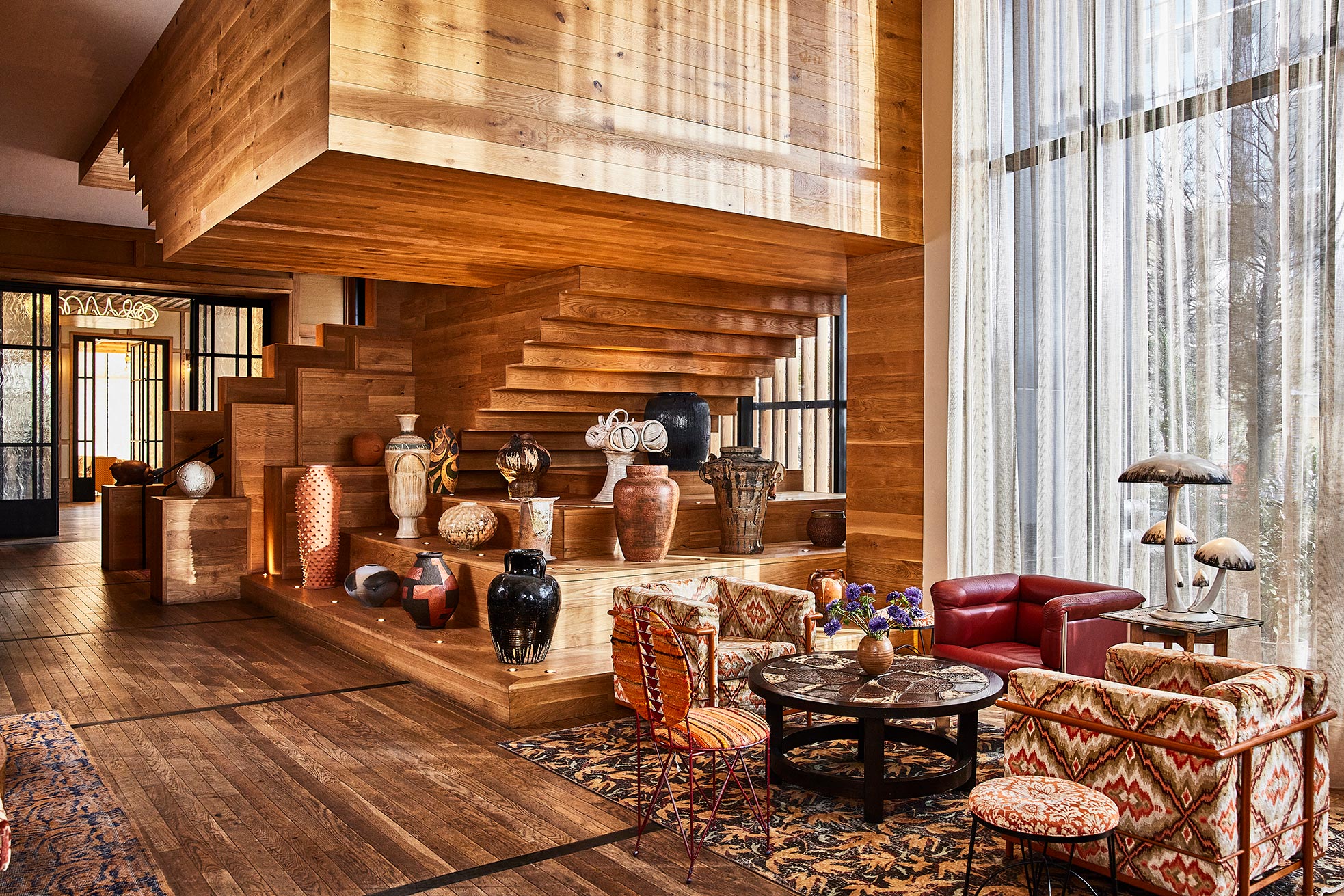 Warm wood lobby with sculptural staircase, ceramic decor, and lounge seating