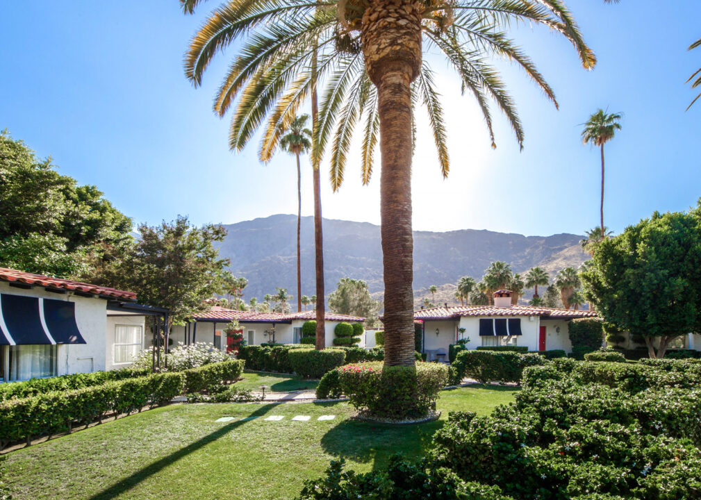 Palm-lined garden courtyard with mountain views and charming bungalow-style rooms.