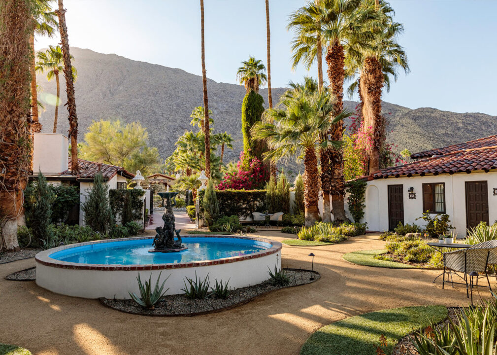 Palm-lined courtyard with central fountain and mountain backdrop.