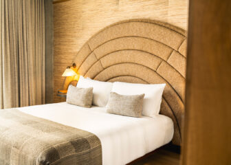 Deluxe king guest room with custom upholstered headboard and warm contemporary interiors