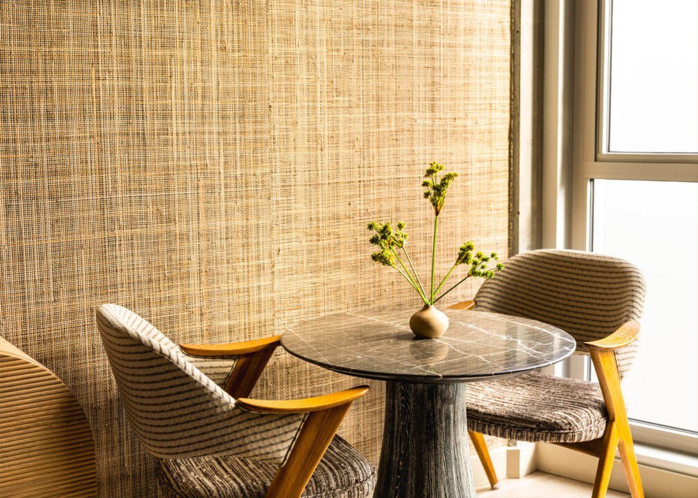 Cozy in room seating area with marble table, textured chairs, and natural light by the window