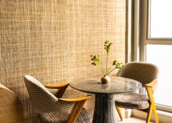 Cozy in room seating area with marble table, textured chairs, and natural light by the window
