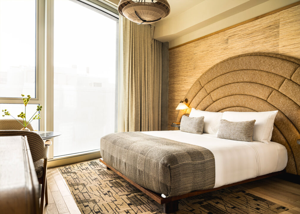 Modern luxury guest room with curved upholstered headboard and floor-to-ceiling window