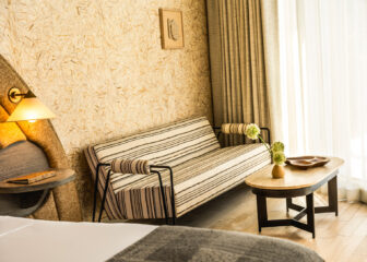 Sunlit hotel suite seating area with striped sofa, textured wallpaper, and modern wood coffee table