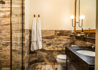 Luxury marble bathroom with glass shower, modern vanity, and plush white bathrobes