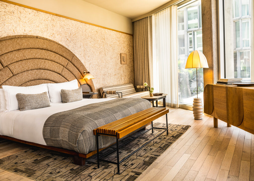 Deluxe Suite with curved upholstered headboard, modern furnishings, and floor-to-ceiling windows