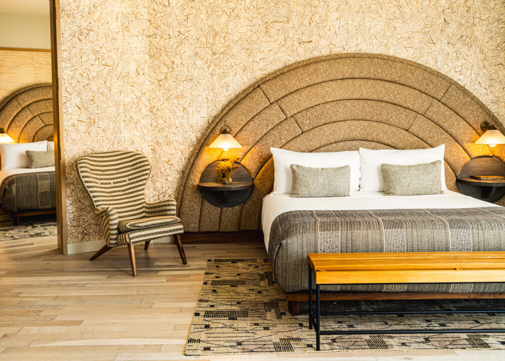 Spacious luxury suite with curved upholstered headboard and warm modern interiors