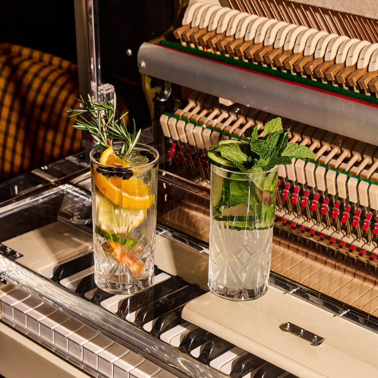 Cocktails set on a piano keyboard with fresh garnishes