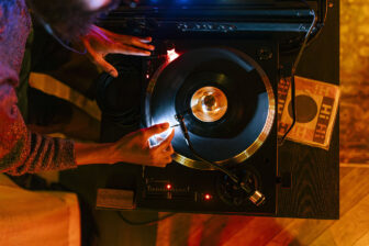 DJ spinning vinyl on a turntable in warm lighting