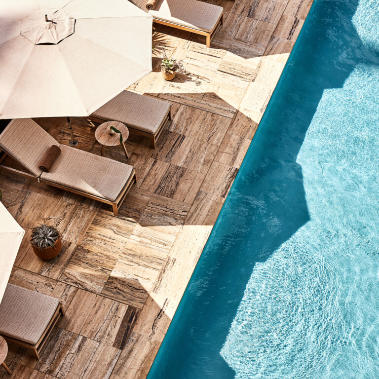 Poolside loungers and umbrellas beside a bright blue swimming pool