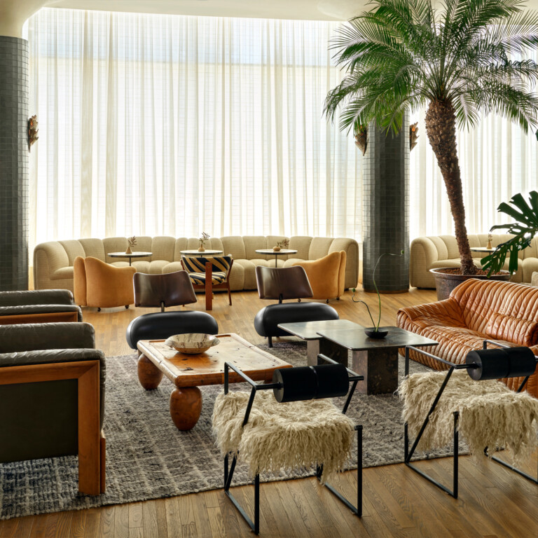 Stylish luxury hotel lounge with modern seating, natural light, and indoor palm tree accents