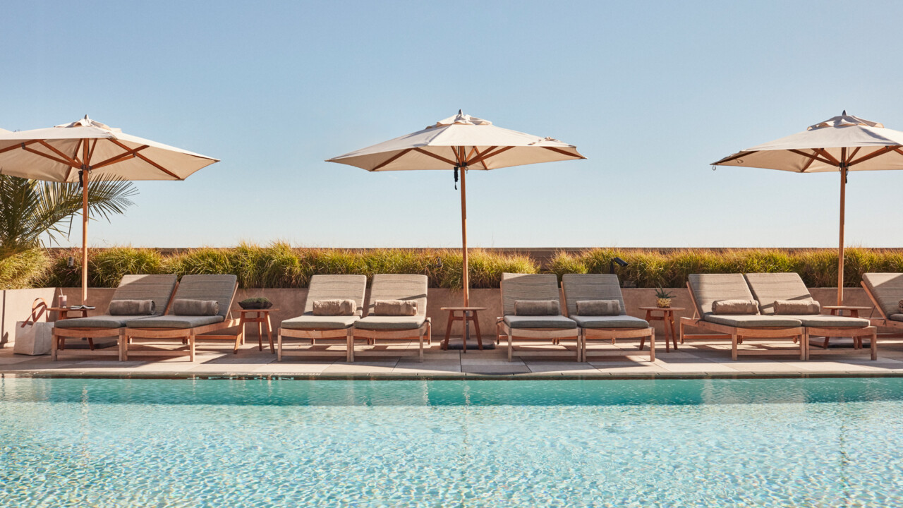 Rooftop pool with sun loungers and umbrellas under clear sky