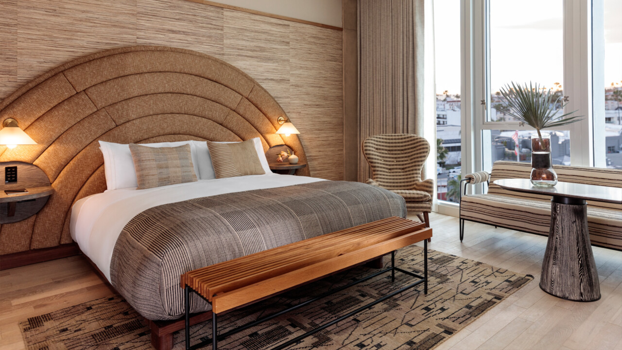 Modern guest room with custom upholstered headboard, floor to ceiling windows, and city views