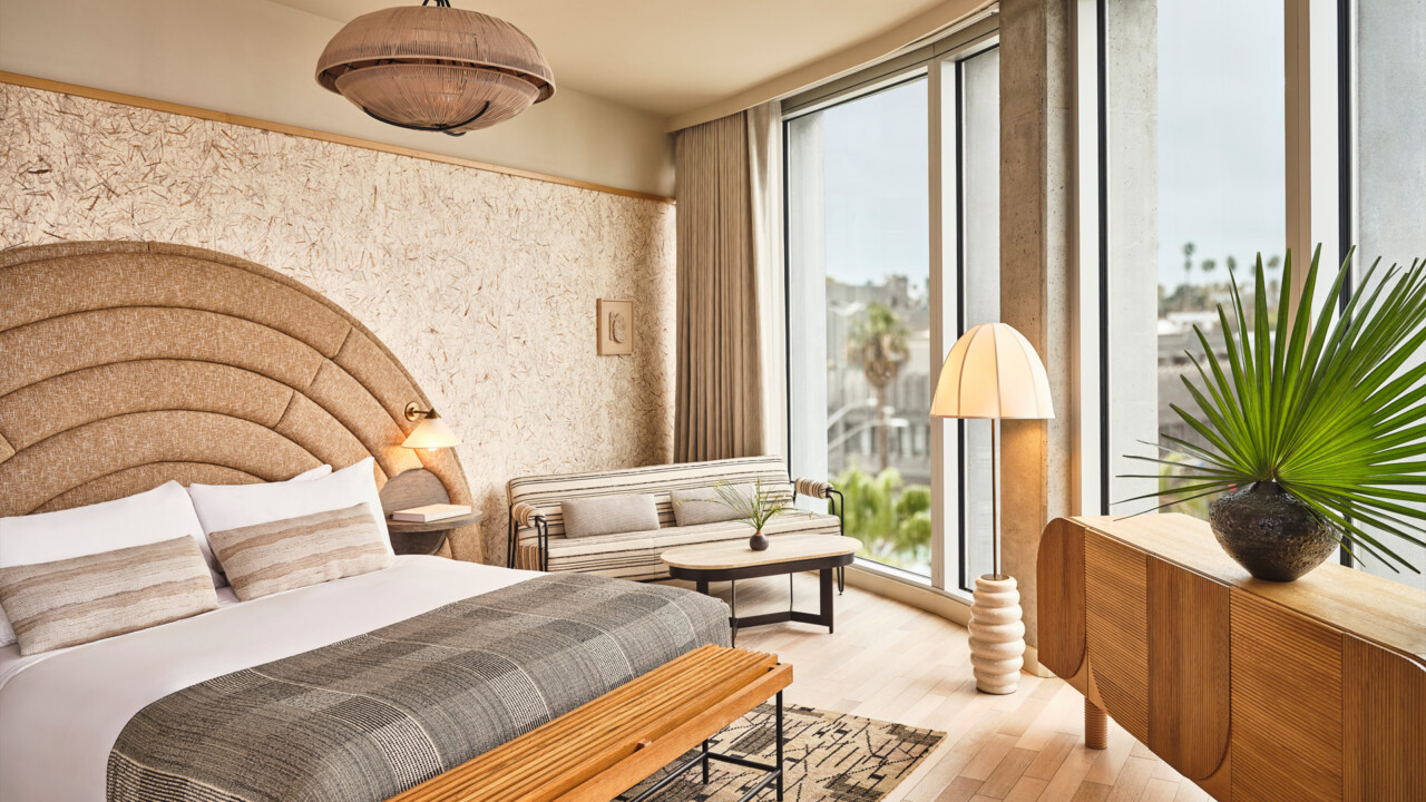 Bright, modern hotel SMP room with a curved headboard, cozy seating, and large windows.