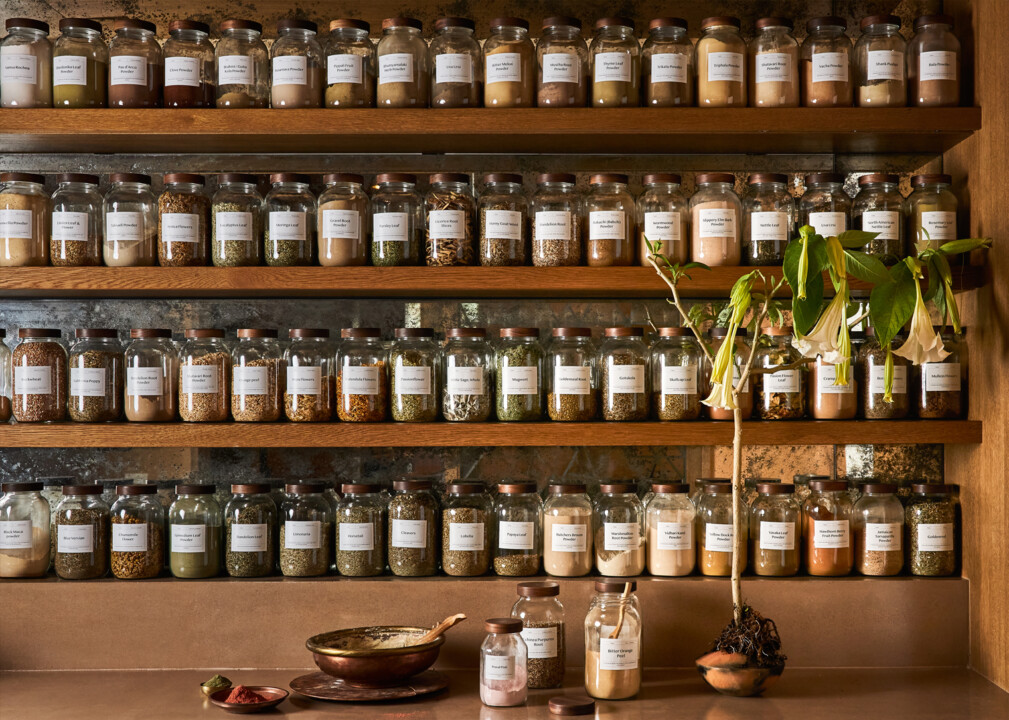 Wall of labeled jars filled with herbs and powders in a spa apothecary setting