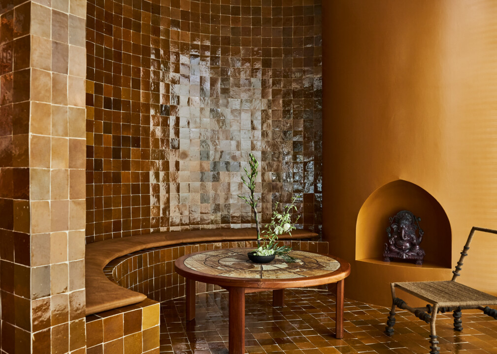Warm-toned spa lounge with tiled seating, round table, and decorative alcove