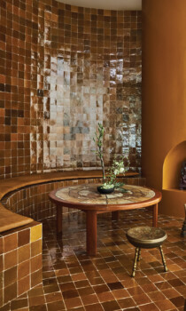 Warm-toned spa lounge with tiled seating, round table, and decorative alcove
