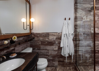 Modern hotel bathroom with marble finishes, glass shower, and plush bathrobes