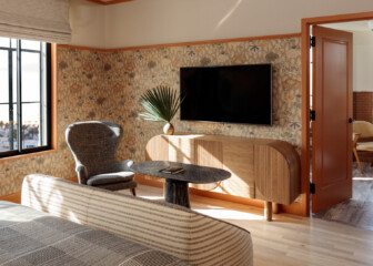 Stylish hotel suite with floral wallpaper, lounge seating, and modern in room entertainment setup
