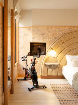 Hotel room with Peloton bike beside bed and window