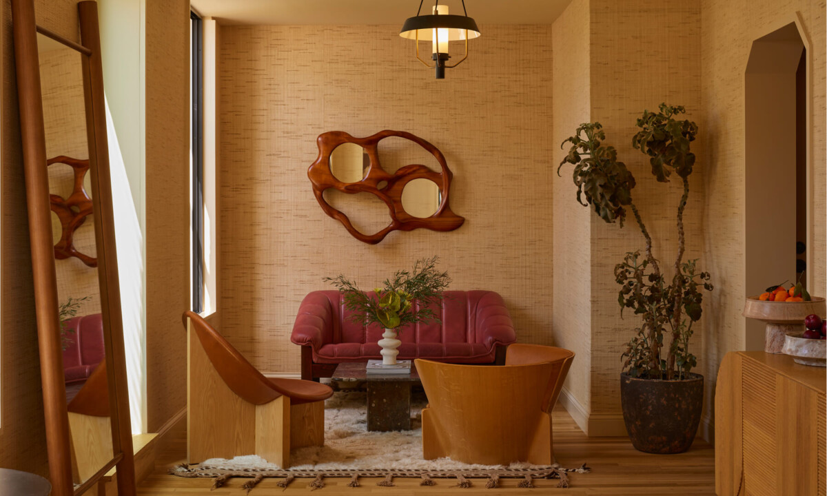 Cozy lounge with red sofa, wood chairs, and sculptural wall decor