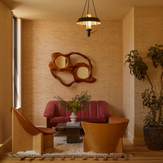 Cozy lounge with red sofa, wood chairs, and sculptural wall decor