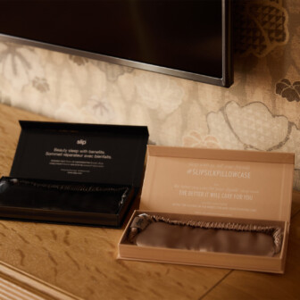 Luxury silk sleep masks displayed on wooden dresser in wellness-focused hotel guest room