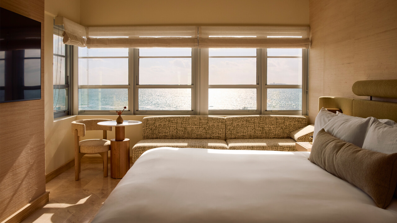 Cozy Shelborne hotel room with a bed and seating area overlooking ocean views through large windows.