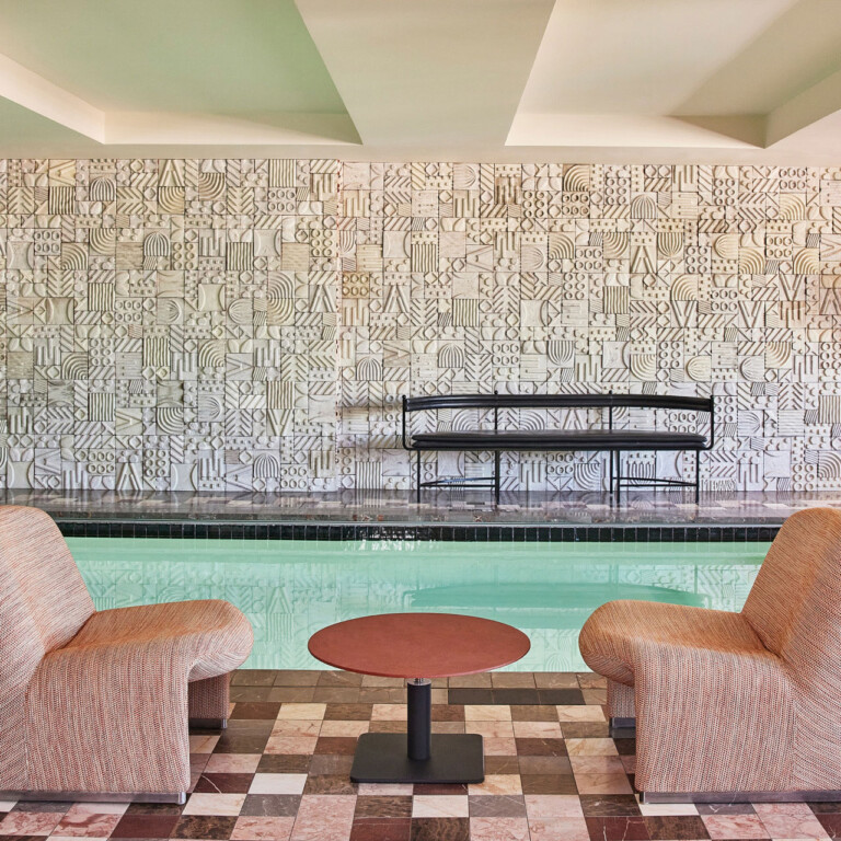 Indoor pool lounge with modern seating and tiled backdrop.