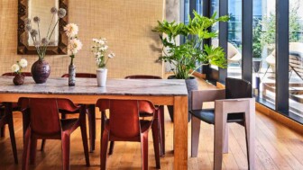 Dining area with wood table, leather chairs, and indoor plants by large windows