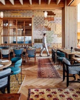Stylish dining room with hardwood floors, area rugs, and multicolored mosaic tiles on the wall