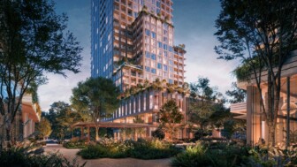 Modern high-rise with lush landscaping and illuminated architectural design.