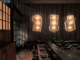 Moody, wood-paneled dining room with sculptural lighting and a refined, minimalist table setting