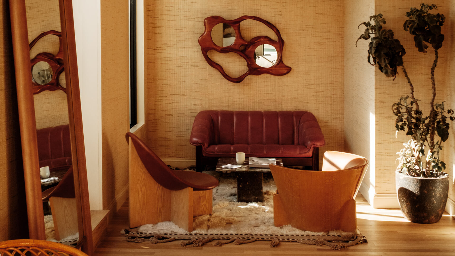 Cozy lounge area with a red sofa, two chairs, a small table, and wall mirror
