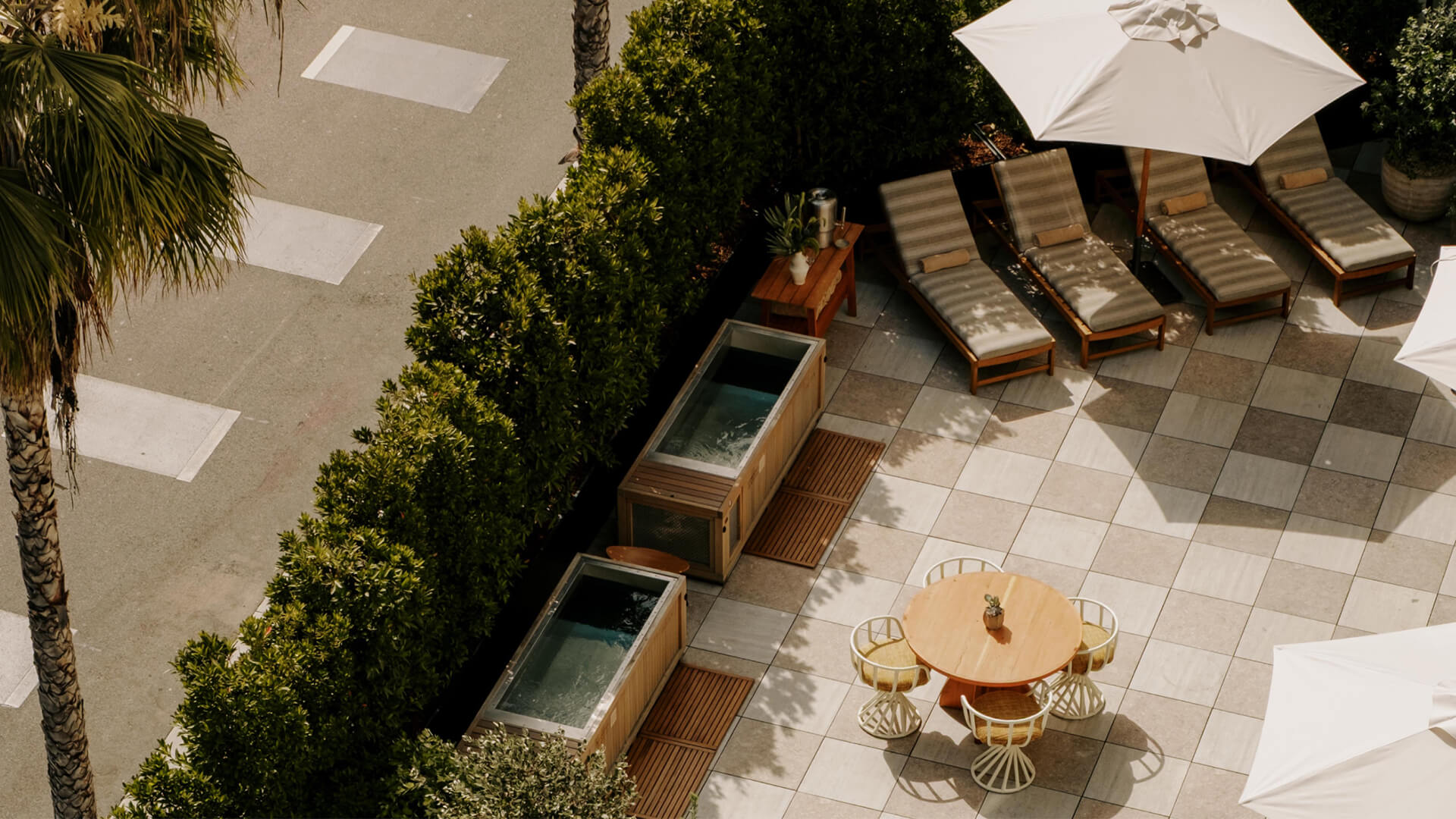 Poolside wellness lounge with cold plunge tubs, sun loungers, and shaded seating at luxury resort courtyard