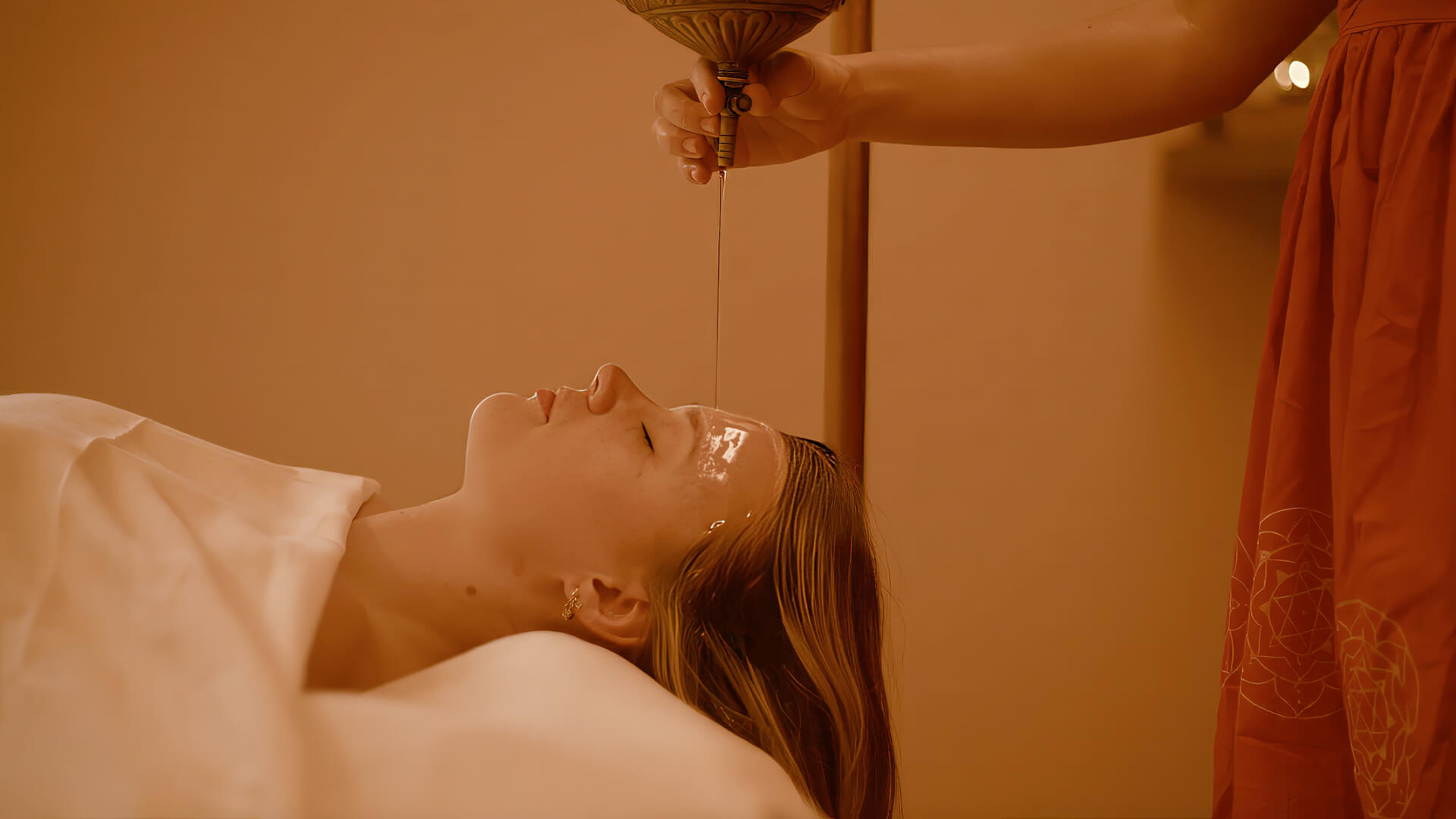 Relaxing Ayurvedic oil therapy treatment at luxury spa with guest receiving forehead massage ritual