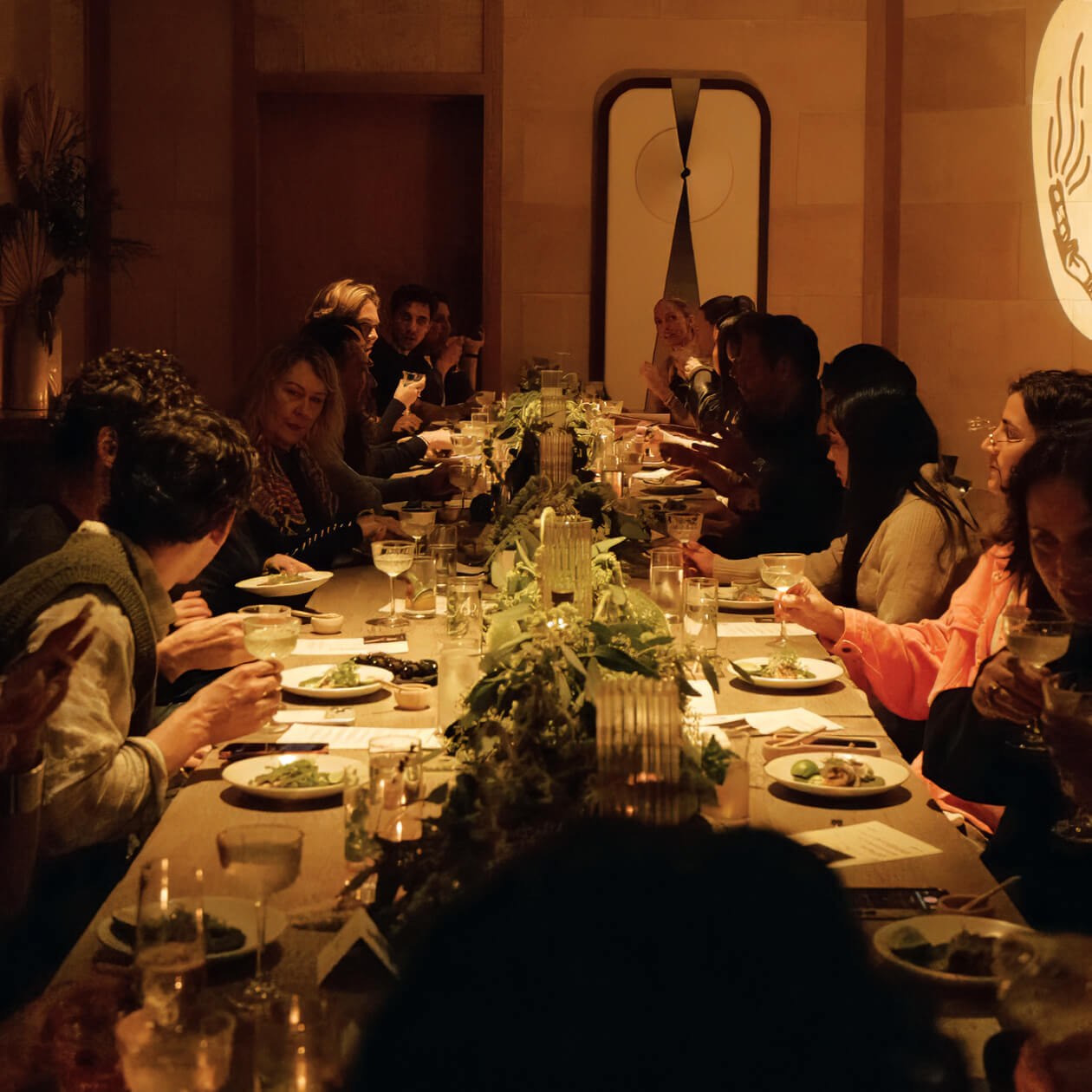 Guests gathered for intimate community dining experience at candlelit luxury wellness and social event
