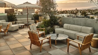 Rooftop terrace with wooden chairs, cushioned sofas, and small tables near plants