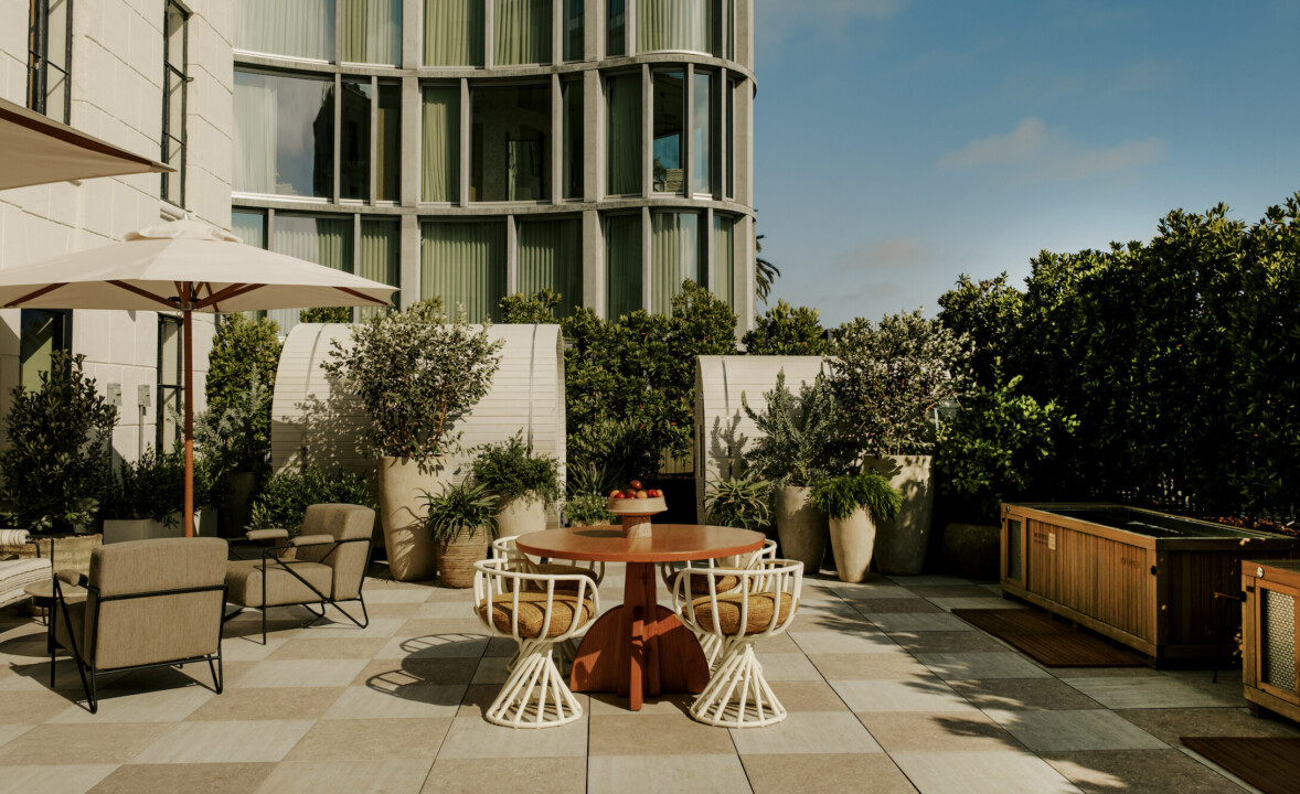Outdoor patio with a table, chairs, and plants beside a building