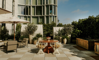 Outdoor patio with a table, chairs, and plants beside a building