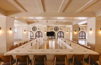 Elegant meeting and event space with warm lighting, arched windows, and spacious conference-style seating in a refined Spanish-inspired setting