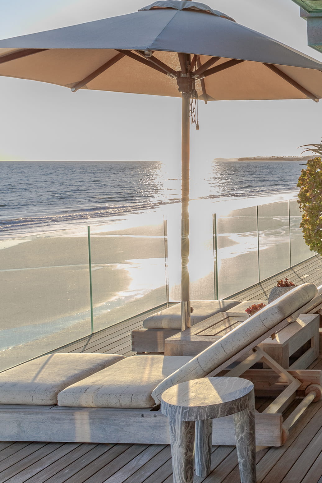 Malibu Beach House beach front terrace with lounge chairs and view of pacific ocean during day time