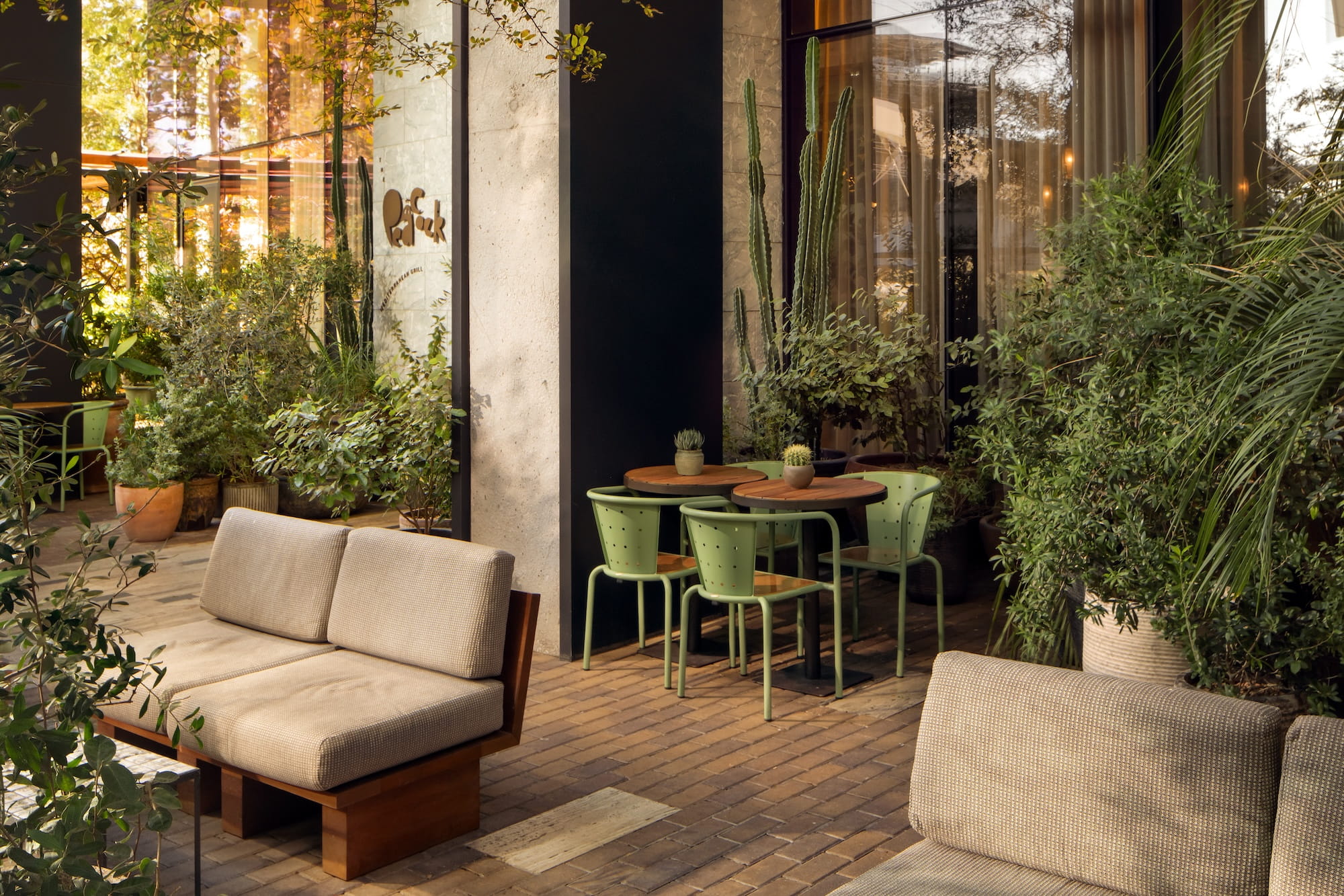 Outdoor patio with lounge seating, café tables, and lush greenery