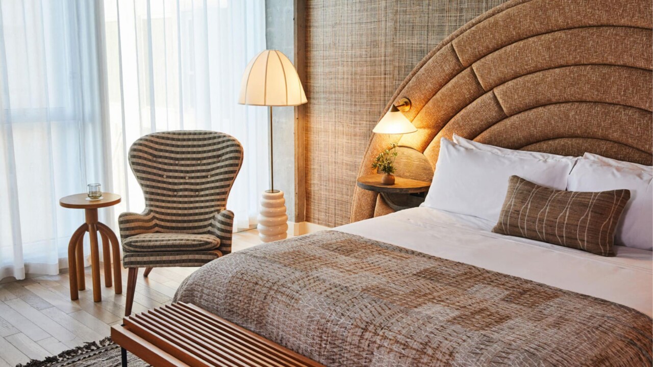 Warm and inviting guest room with textured headboard, cozy seating area, soft lighting, and elegant modern desert-inspired interiors